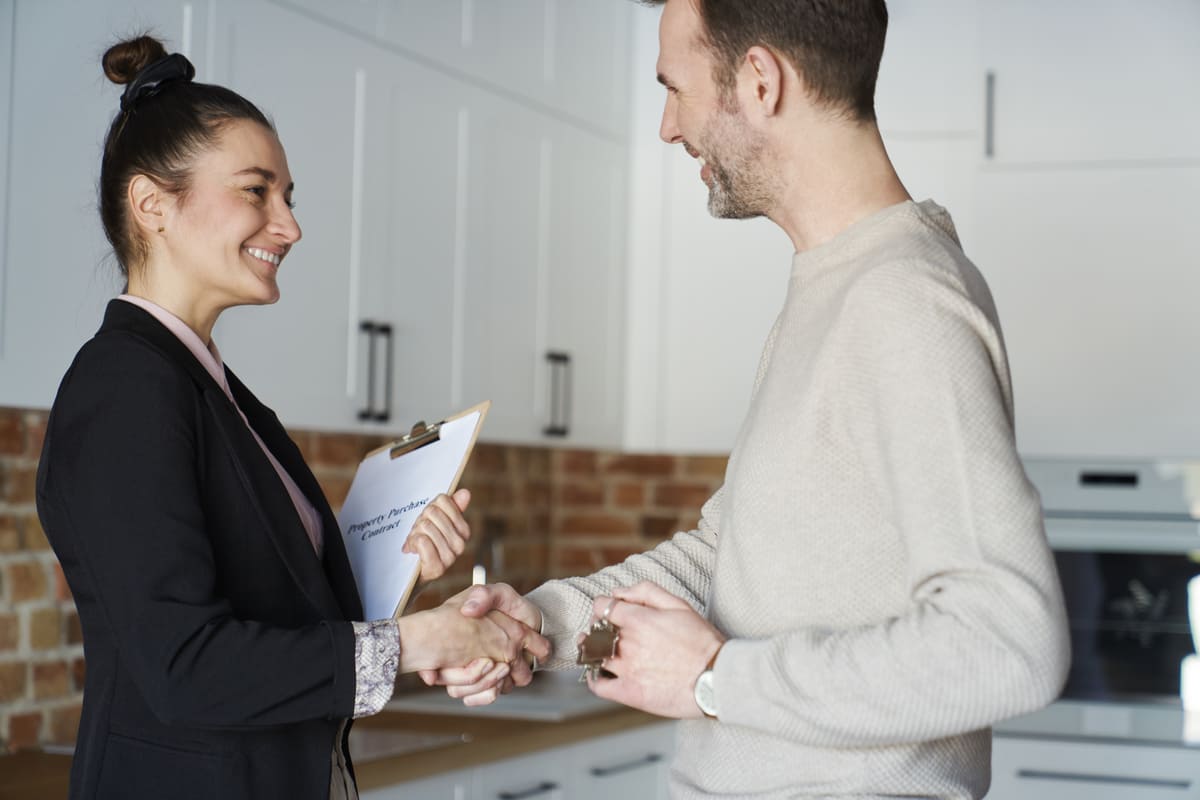 A woman with a clipboard talking to a man inside of a property