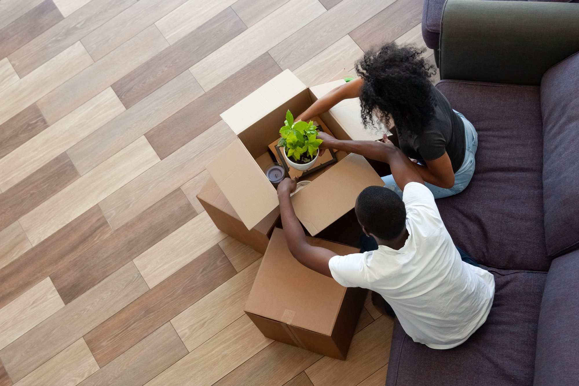 Black couple unpacking cardboard boxes in living room moving in out new home, african tenants renters packing stuff preparing for relocation house renovation