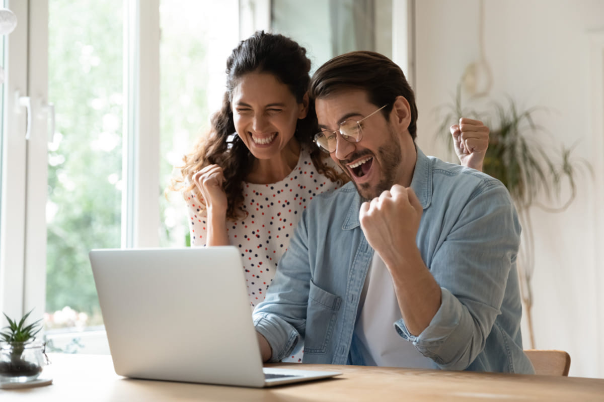 A happy couple looks at a laptop - benefits of the reliable property management Baltimore offers