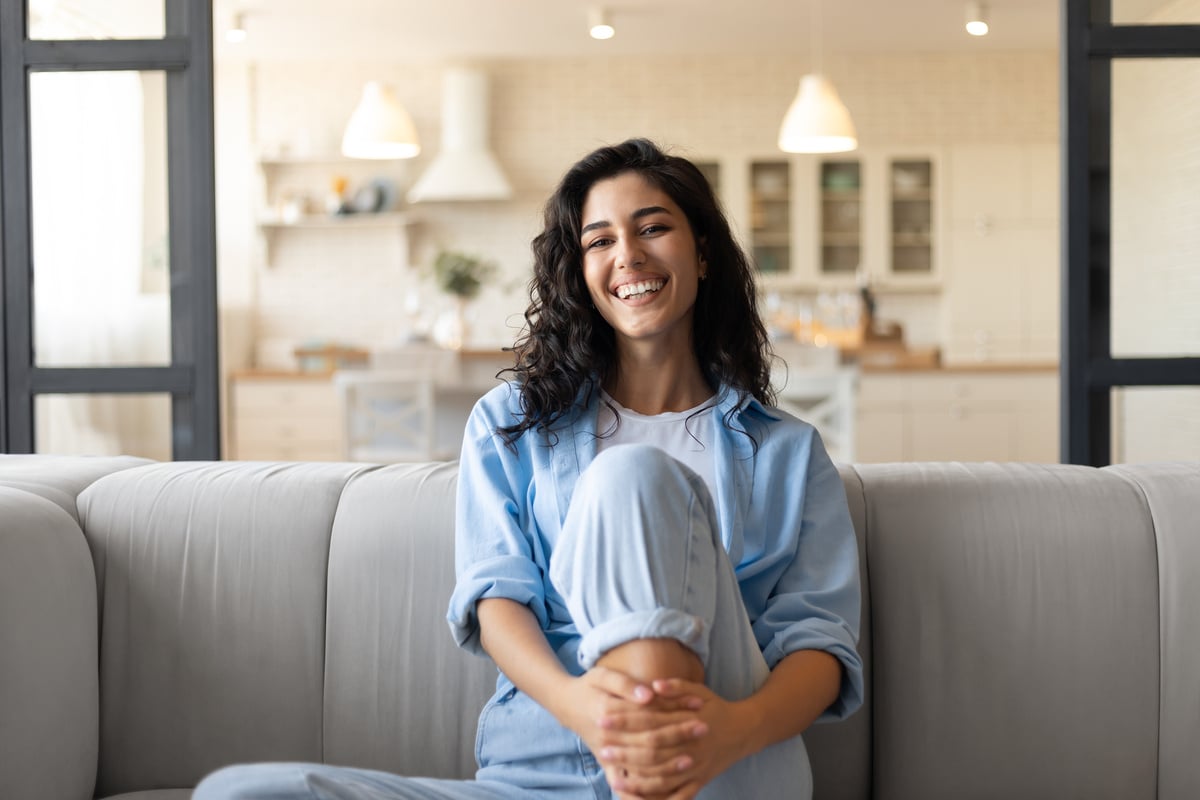 A happy woman sitting on the couch in her home