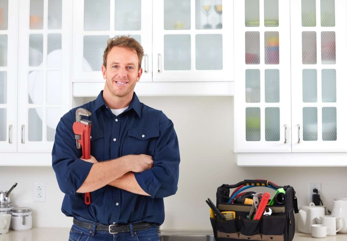 A plumber with a wrench in a home, Baltimore property management services concept