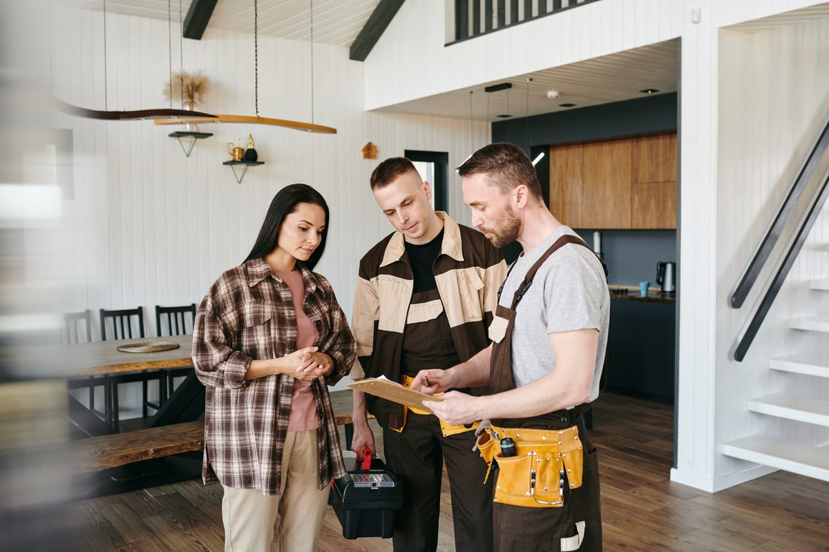 A woman speaking with two maintenance workers in her home