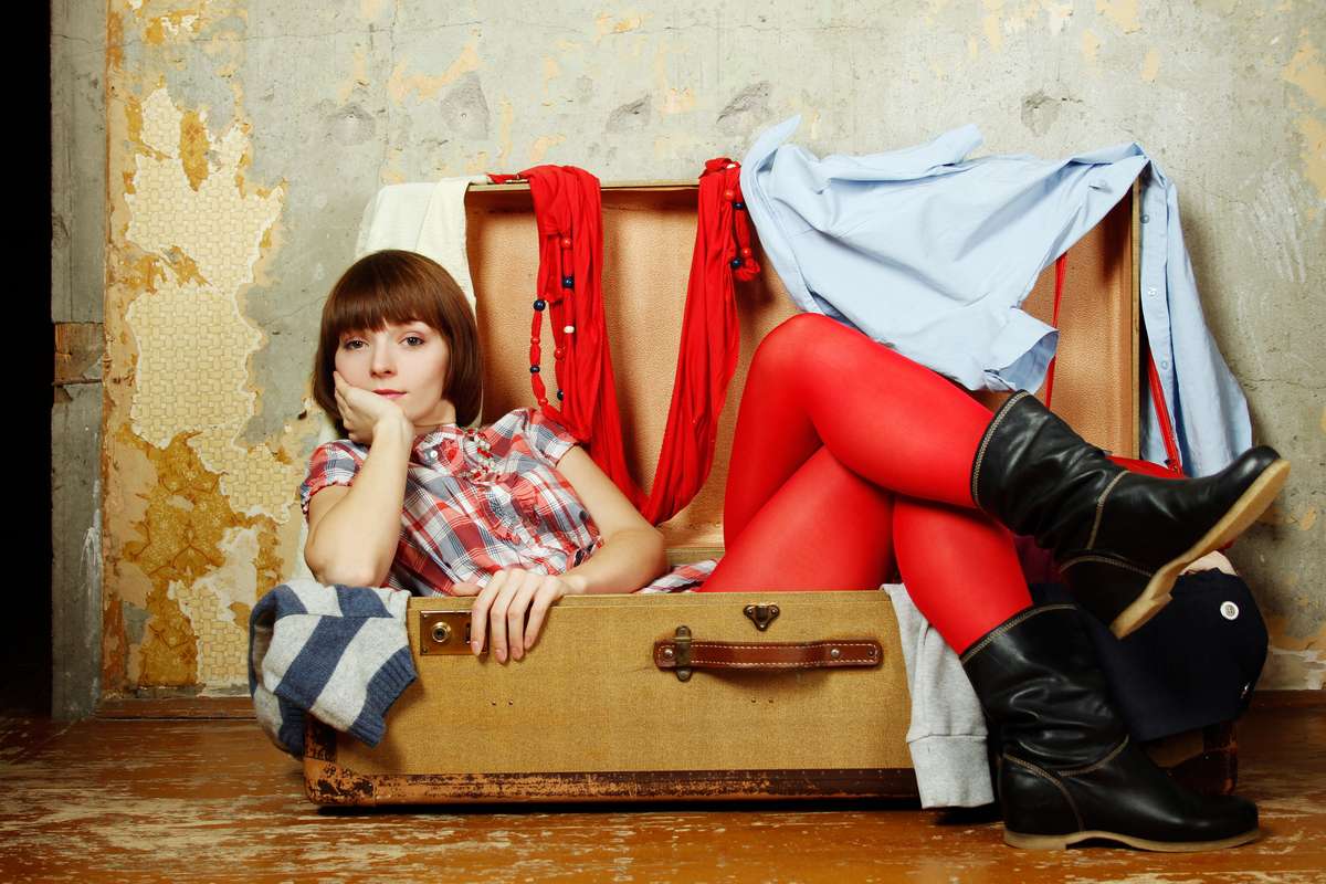 Attractive woman sitting in a suitcase