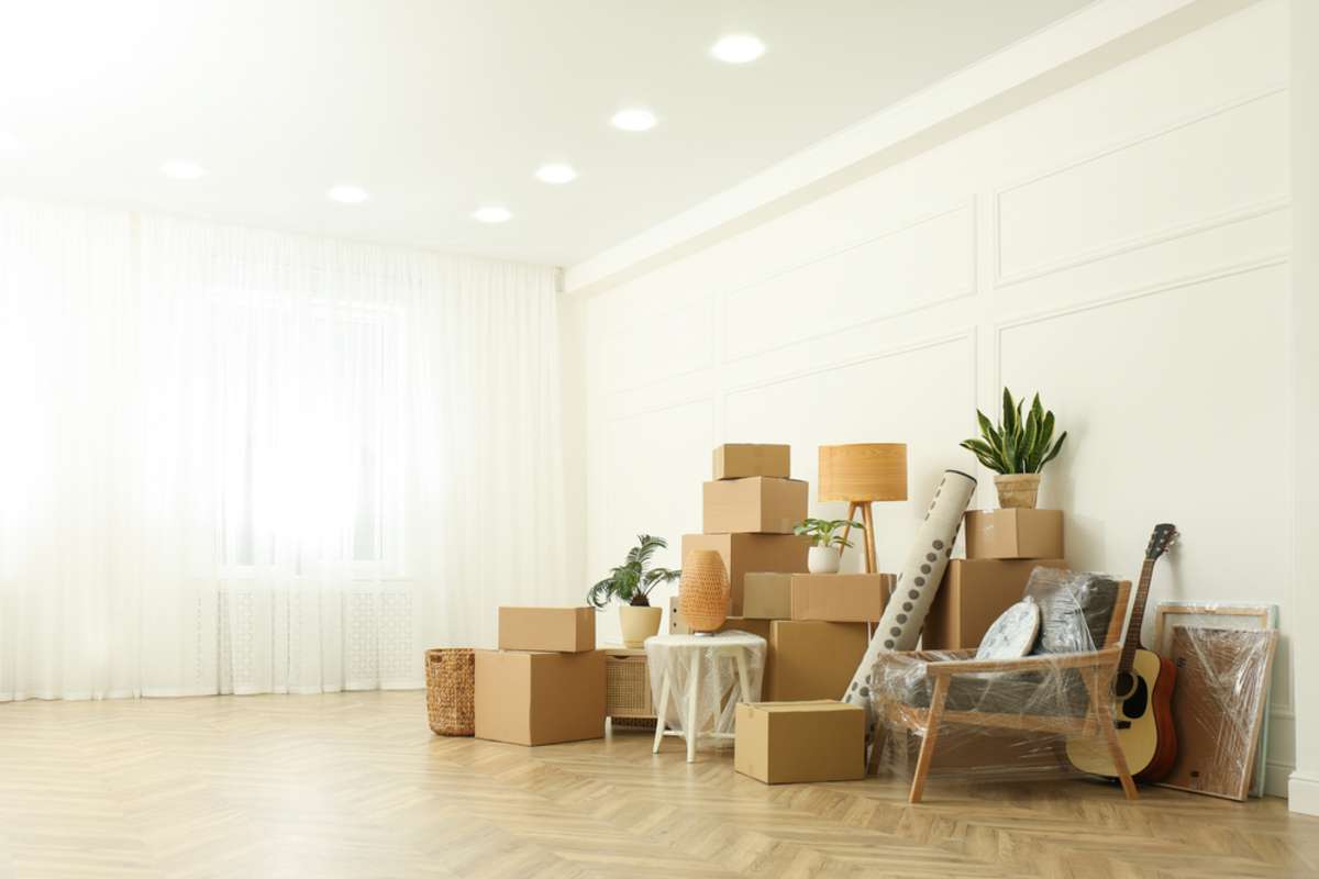 Cardboard boxes and household stuff indoors, space for text
