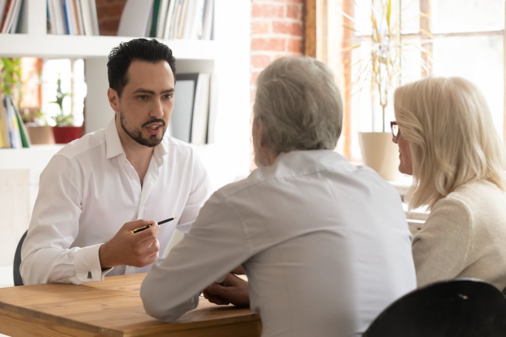 Confident property manager consulting old senior couple clients 