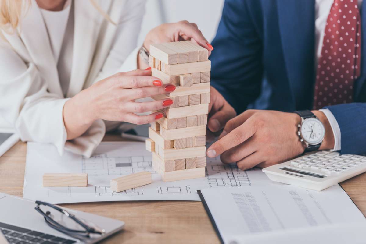 Cropped view of risk managers sitting at workplace near stacked wooden blocks