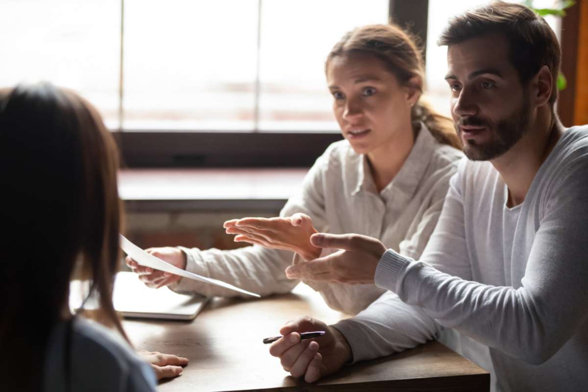 Disappointed young couple meeting with realtor or designer dispute complain about contract regulations