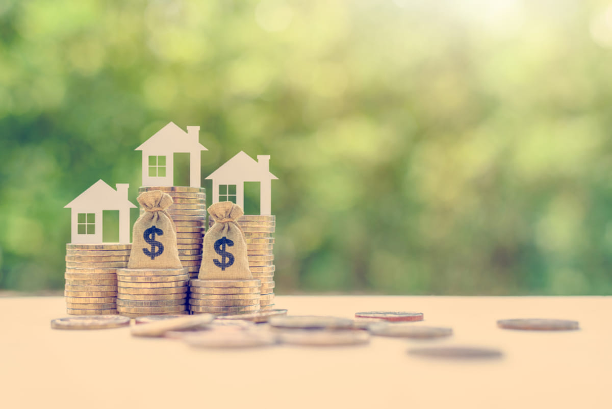 Model houses with stacks of coins - rent vs sell home to build equity concept