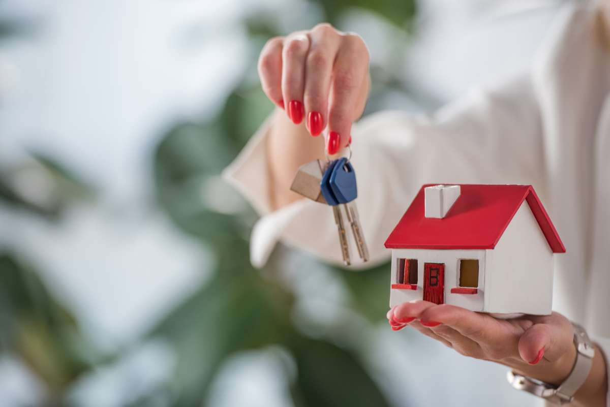 Partial view of businesswoman showing house model and keys