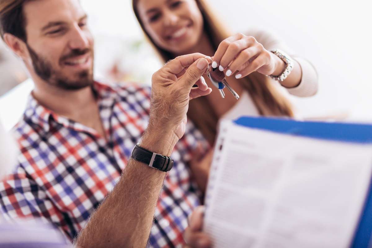 Real estate agent giving keys to couple of customers