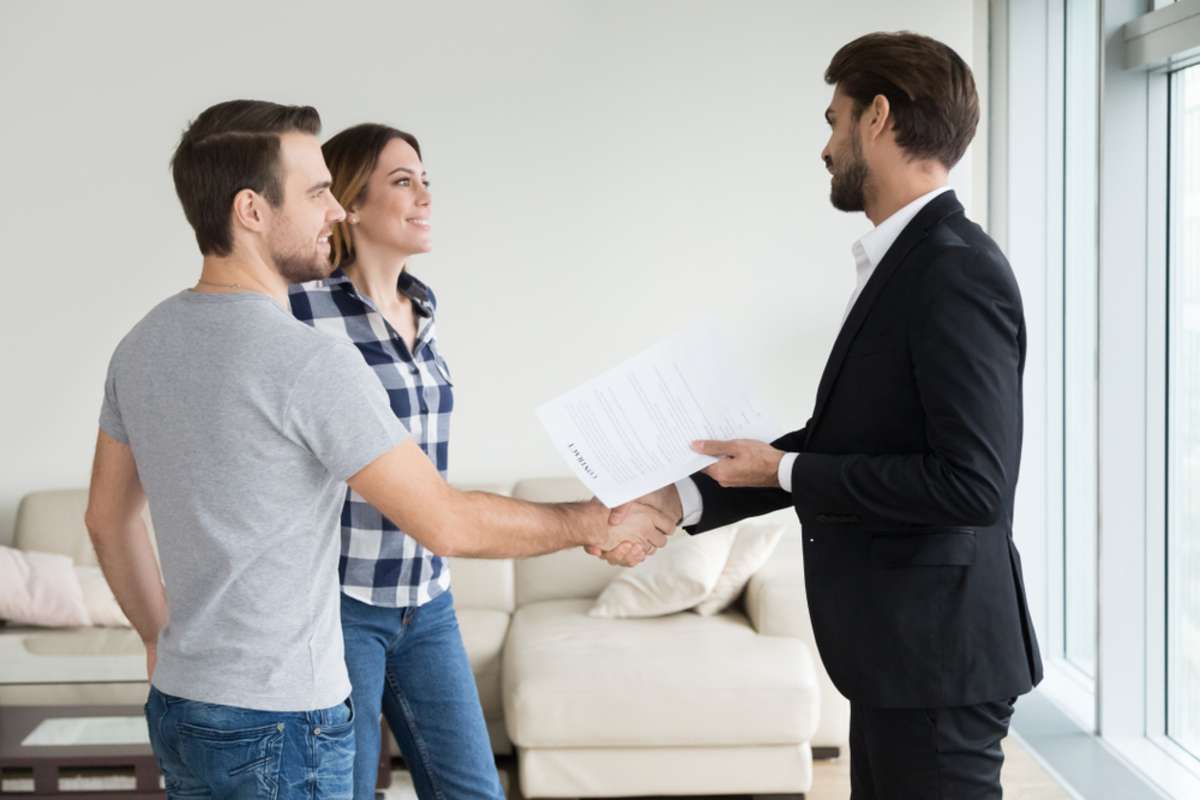 Realtor or landlord handshaking couple buyers tenants make real estate deal holding rental agreement or sale purchase contract