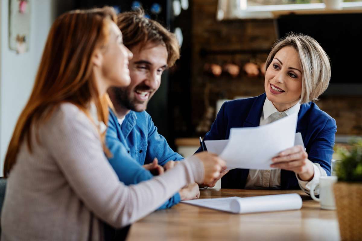 Smiling real estate agent communicating with a couple during a meeting at their home