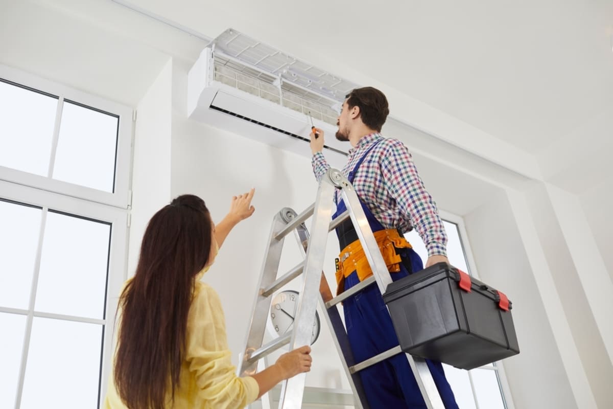 Technician from the AC Maintenance and Repair Service climbs a ladder with his toolbox