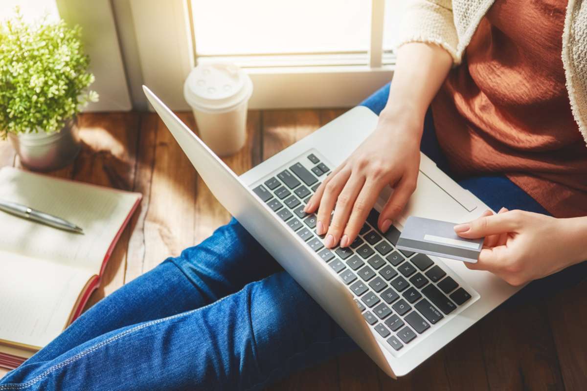 Woman is holding credit card and using laptop computer