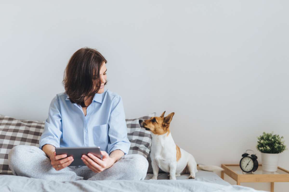 Woman sitting on a bed with a small dog, reliable property management Baltimore concept