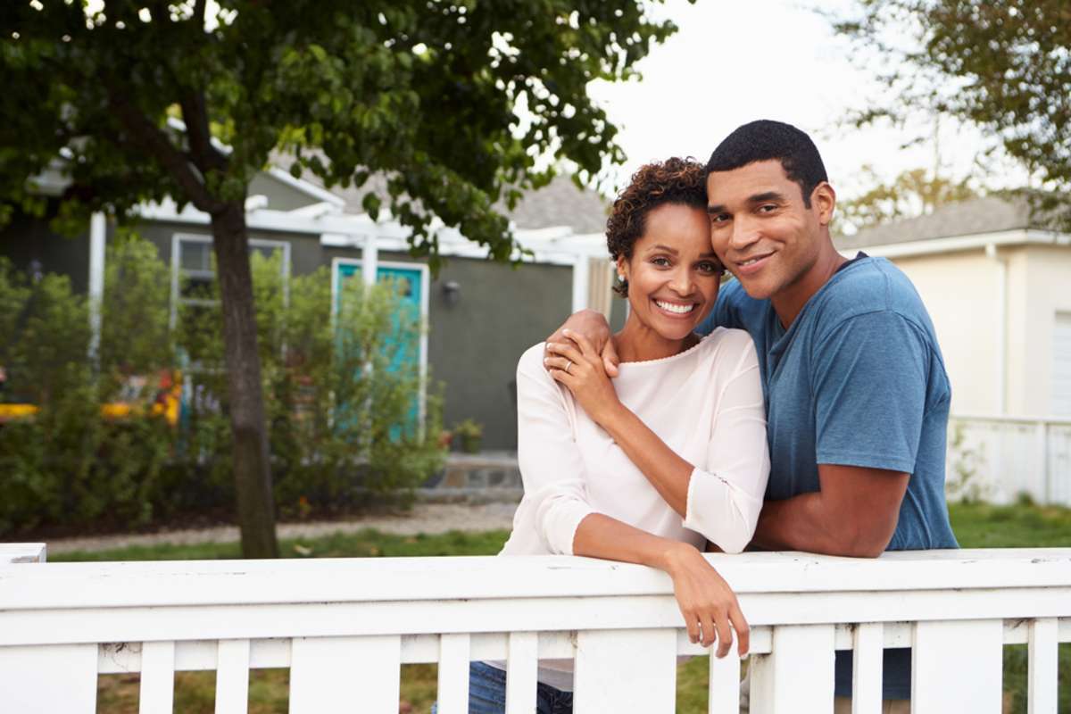 Young African American couple embrace outside their house