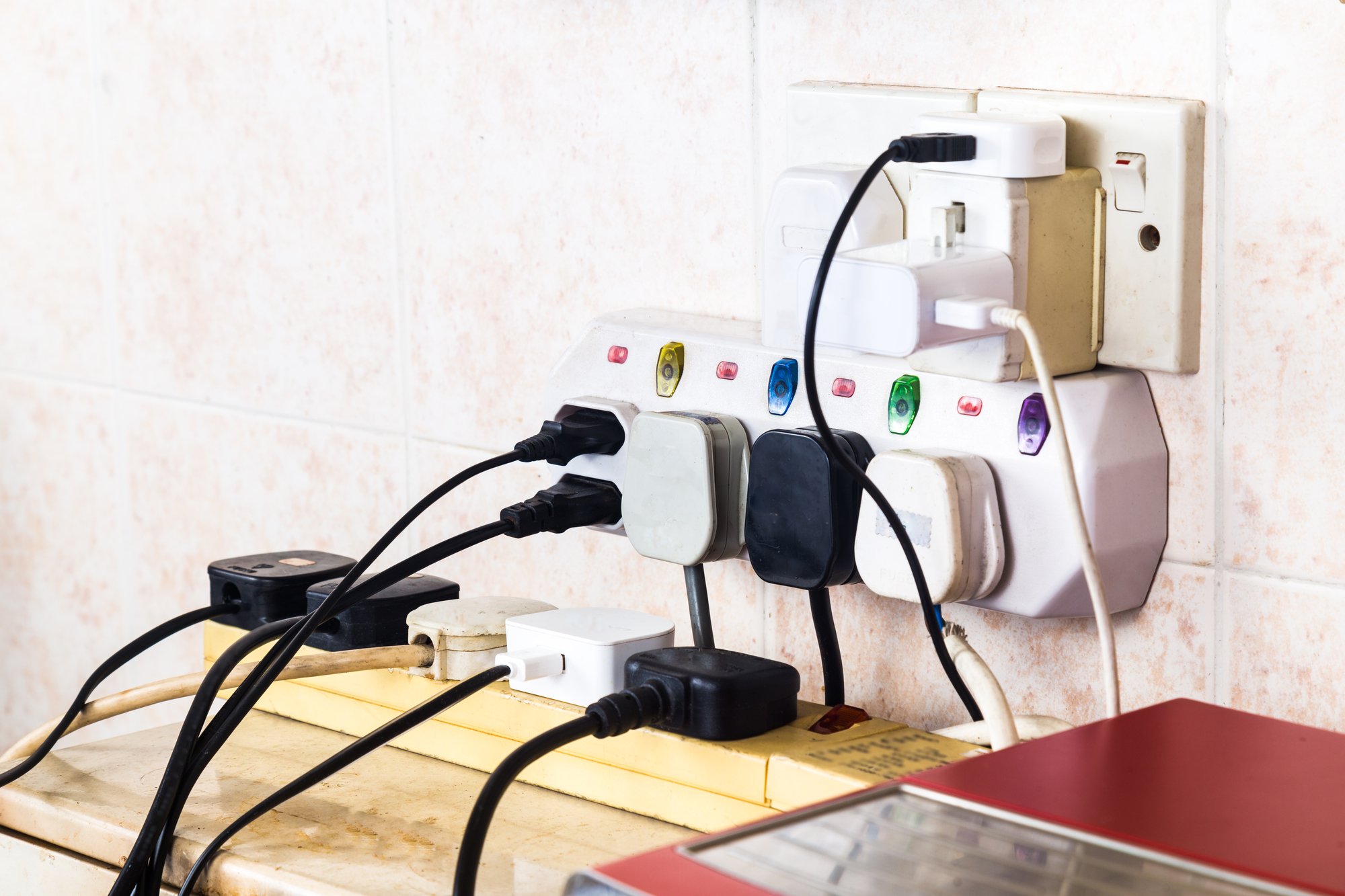 Multiple electricity plugs on adapter risk overloading and dange