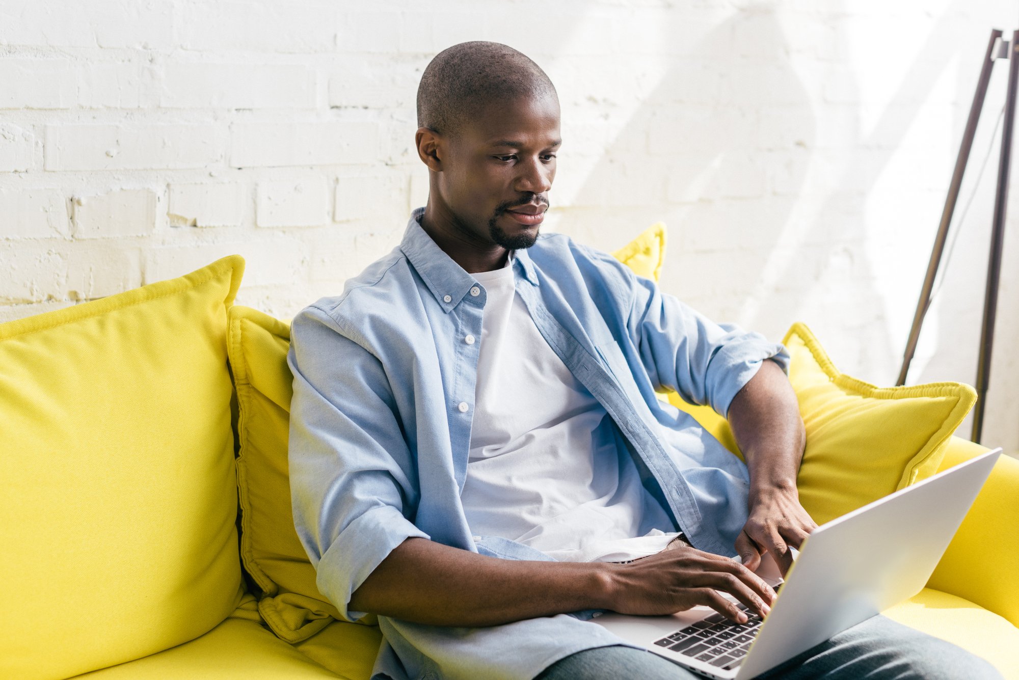 Portrait of african american man using laptop on sofa at home