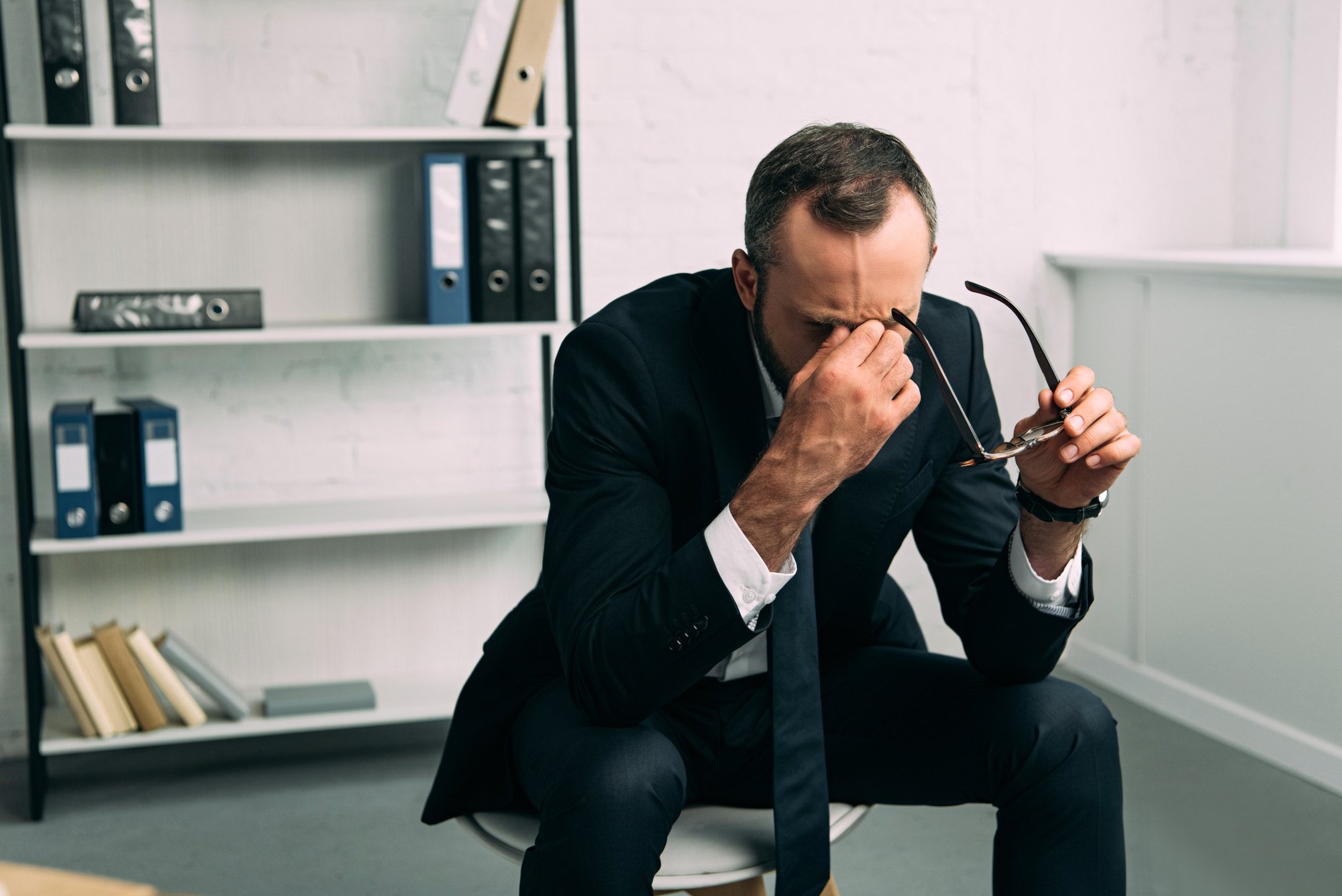 Portrait of overworked businessman in suit with eyeglasses in office