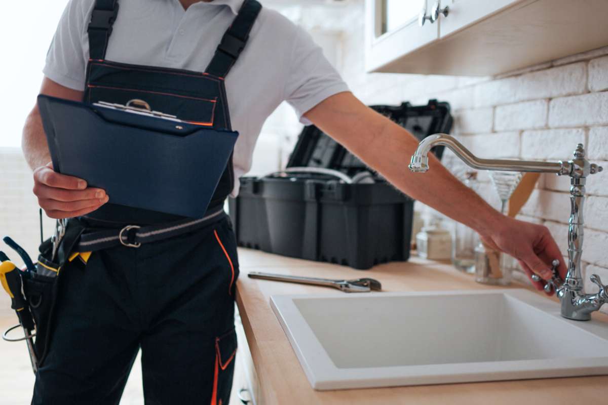 A plumber fixes a leaky sink, rental property maintenance concept