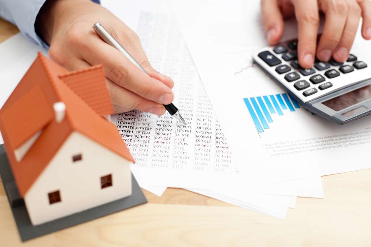 Close-up of a spreadsheet with a model home and calculator, monitoring rental property cash flow concept. 