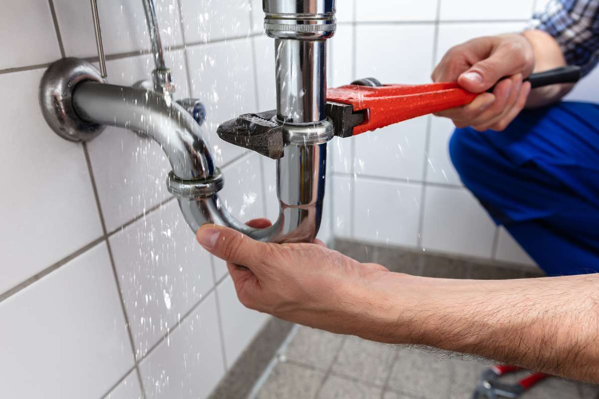 Male Plumbers Hand Repairing Sink Pipe Leakage With Adjustable Wrench