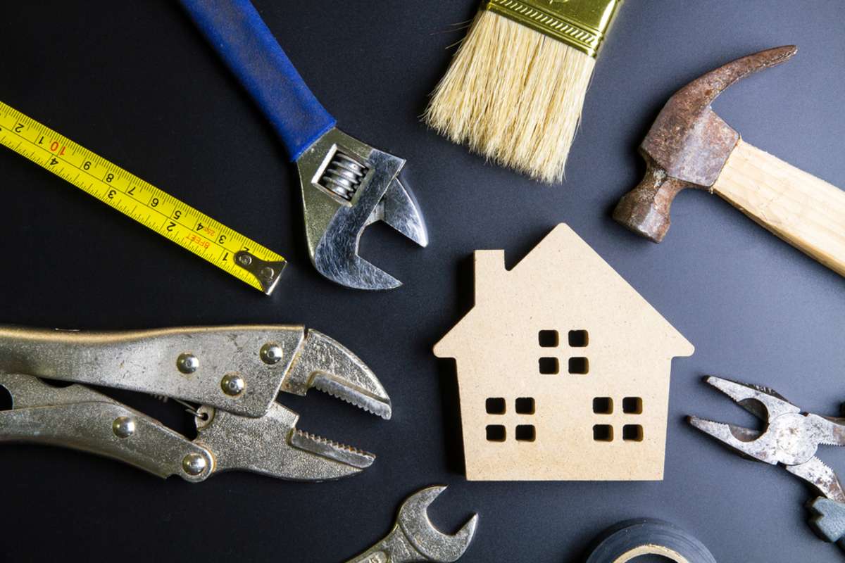 Wooden house toy and construction tools on black background with copy space