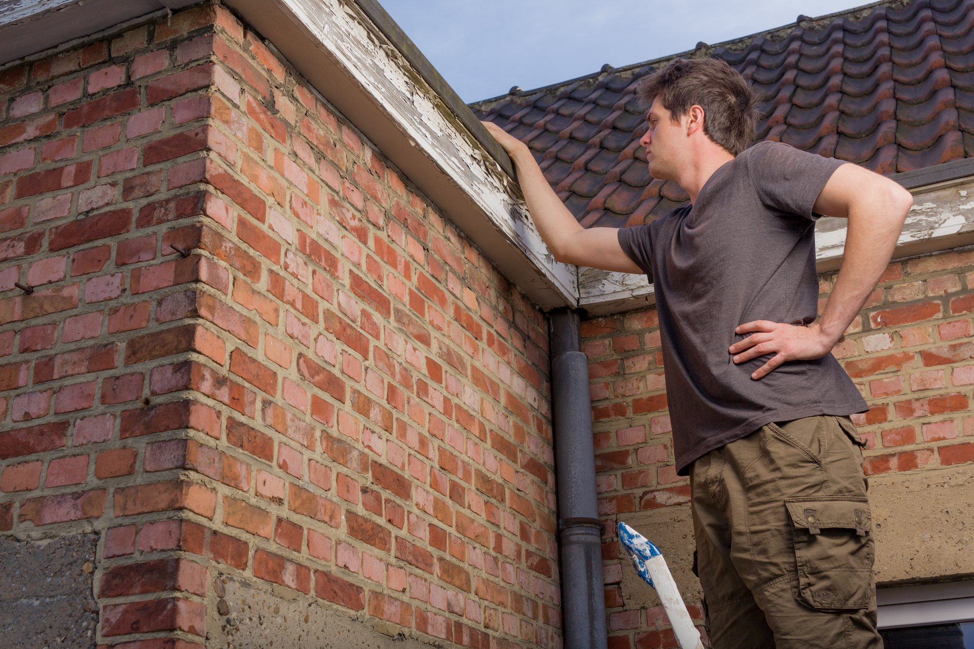 Young man inspecting the roof of an old house