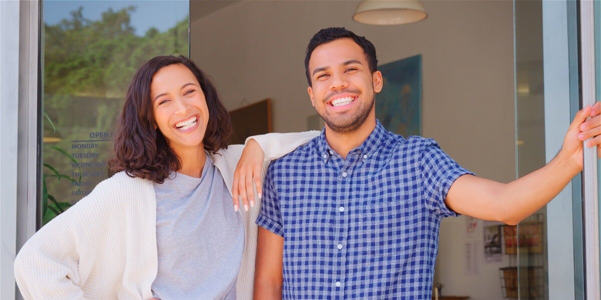 A happy man and woman standing outside of their home