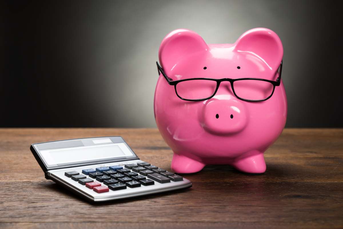 A piggy bank next to a calculator for managing a rental property maintenance budget