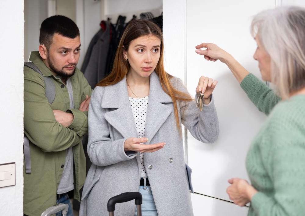 Dissatisfied landlord receiving keys from married couple tenants