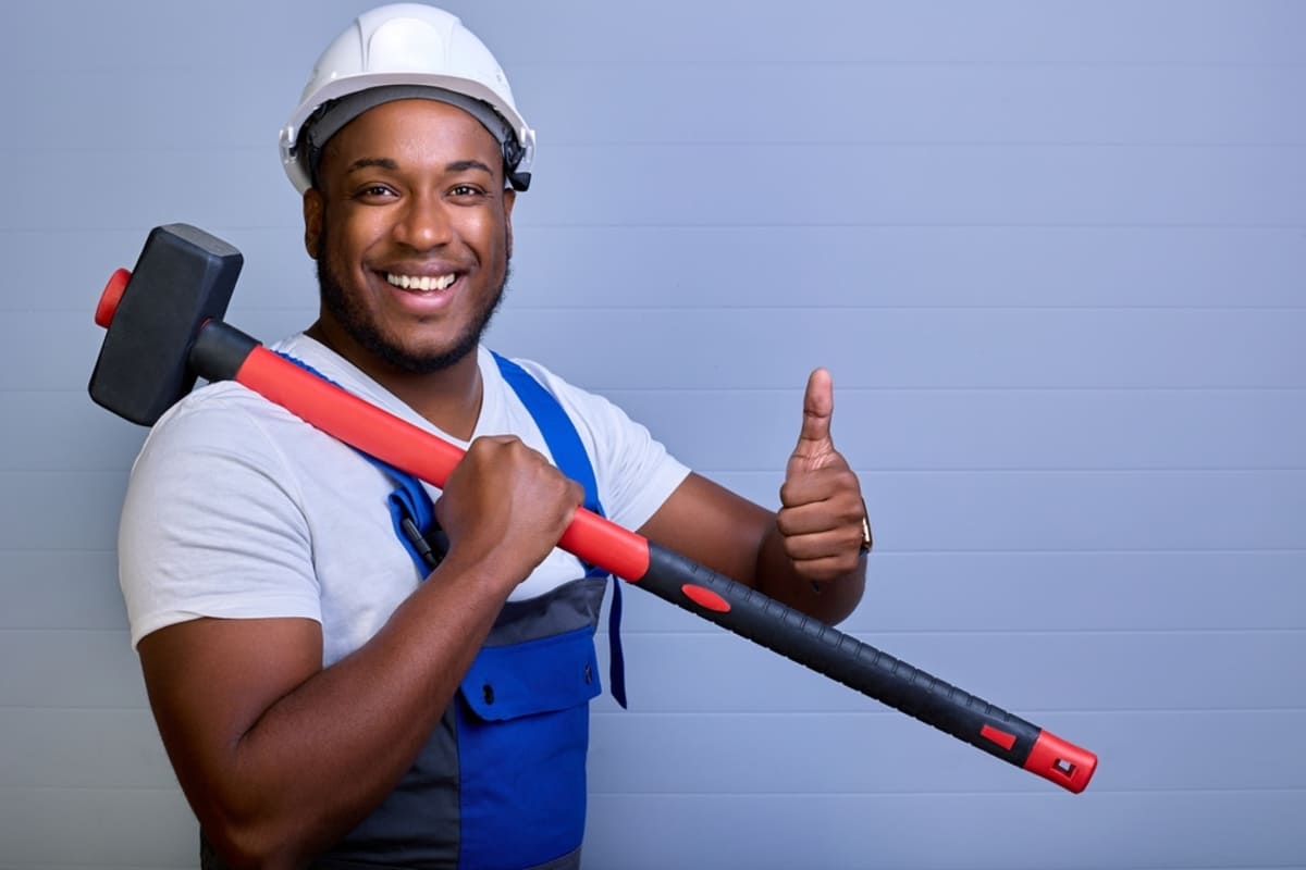 Man with a large sledgehammer and hard hat, DIY rental property maintenance concept