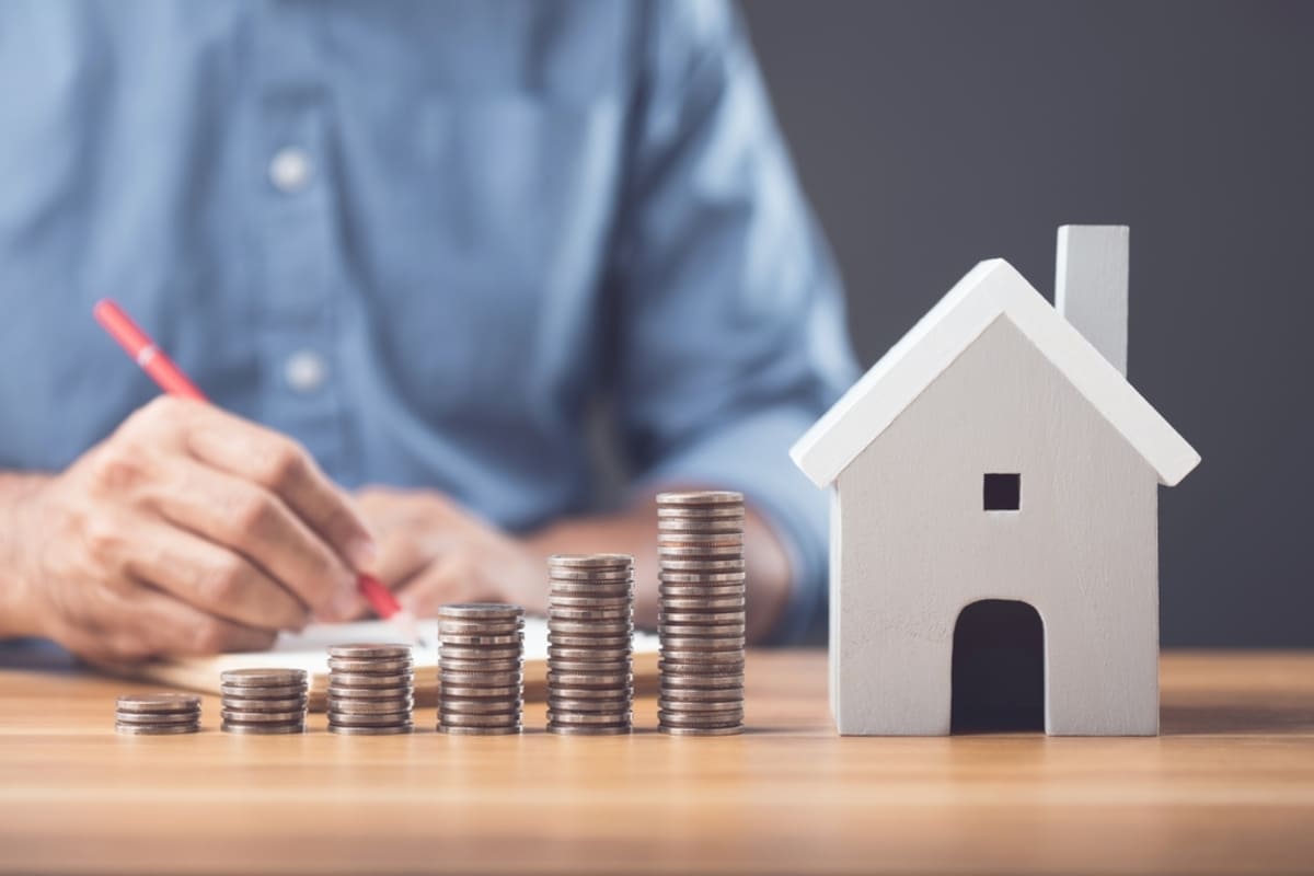 Stacks of coins next to a model house, making money from investment properties in Maryland concept