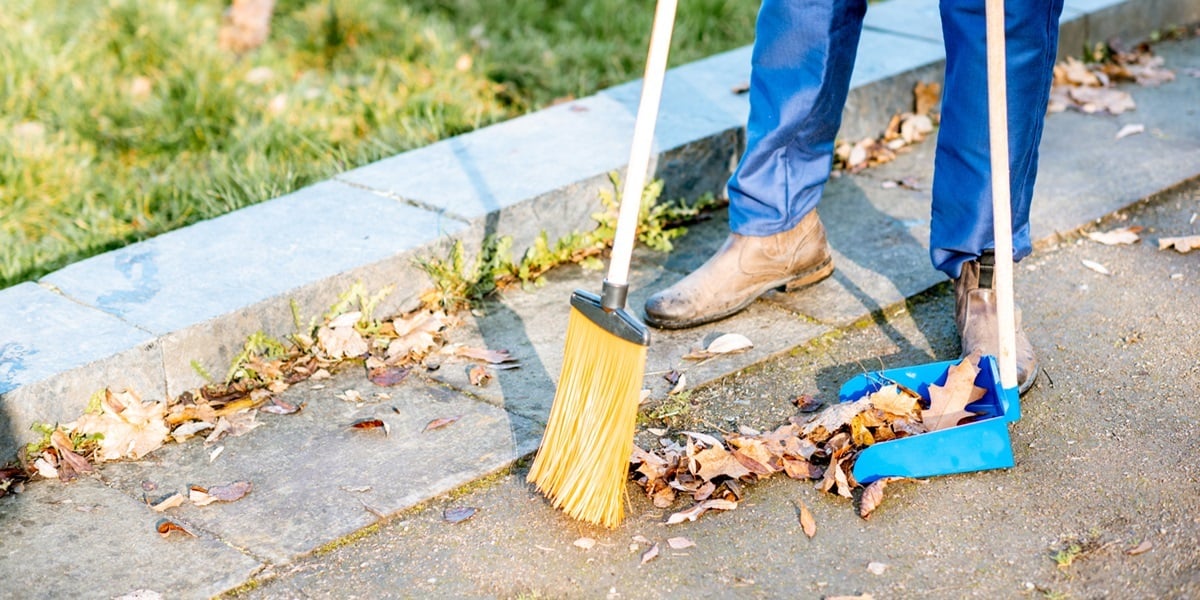 Sweeping leaves with broom and scoop