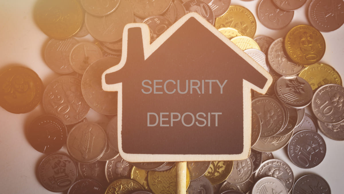 Word SECURITY DEPOSIT on mini card with coins on white table.