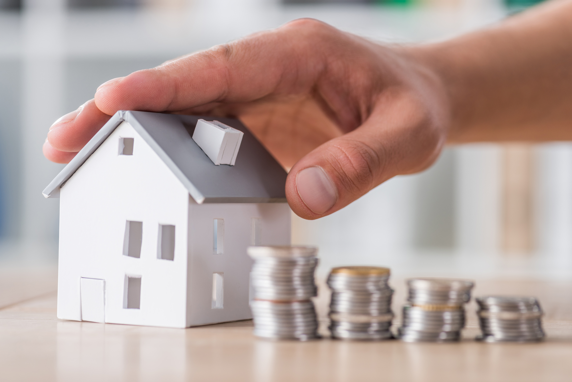 House model beside a stack of coins