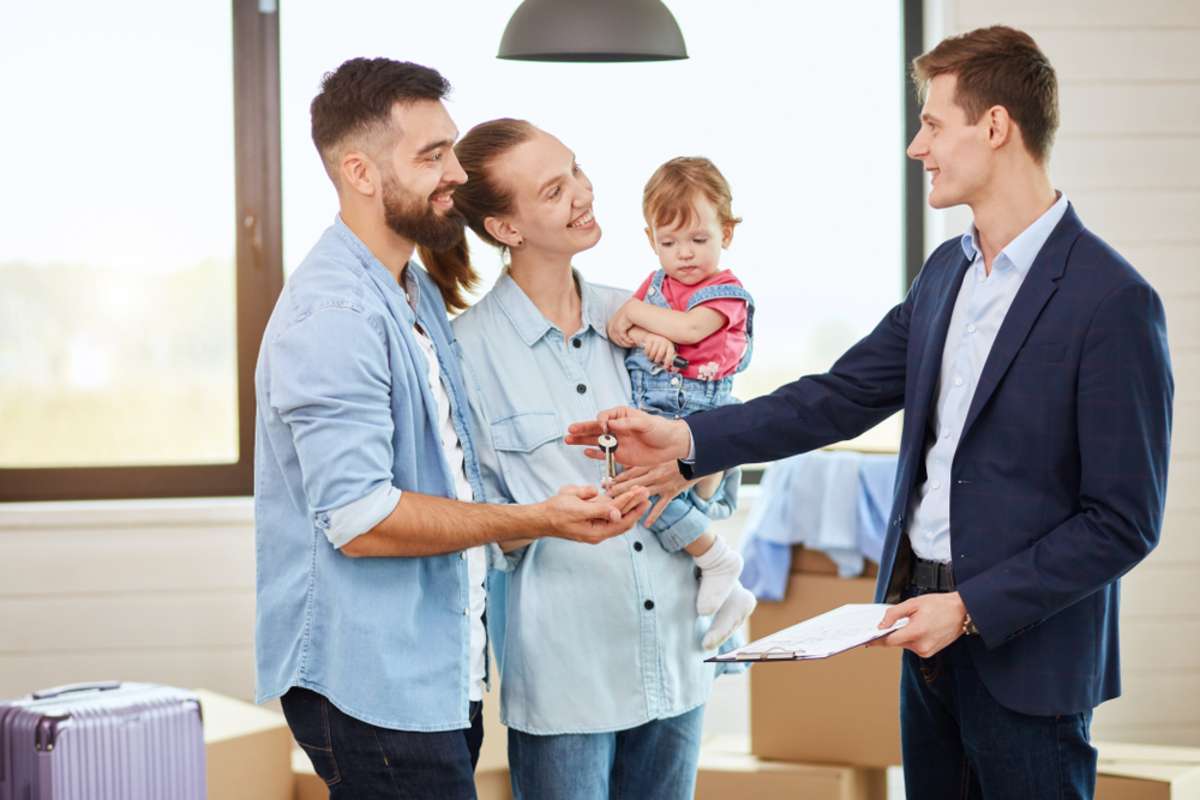 Caucasian family of three people take keys new big house from realtor